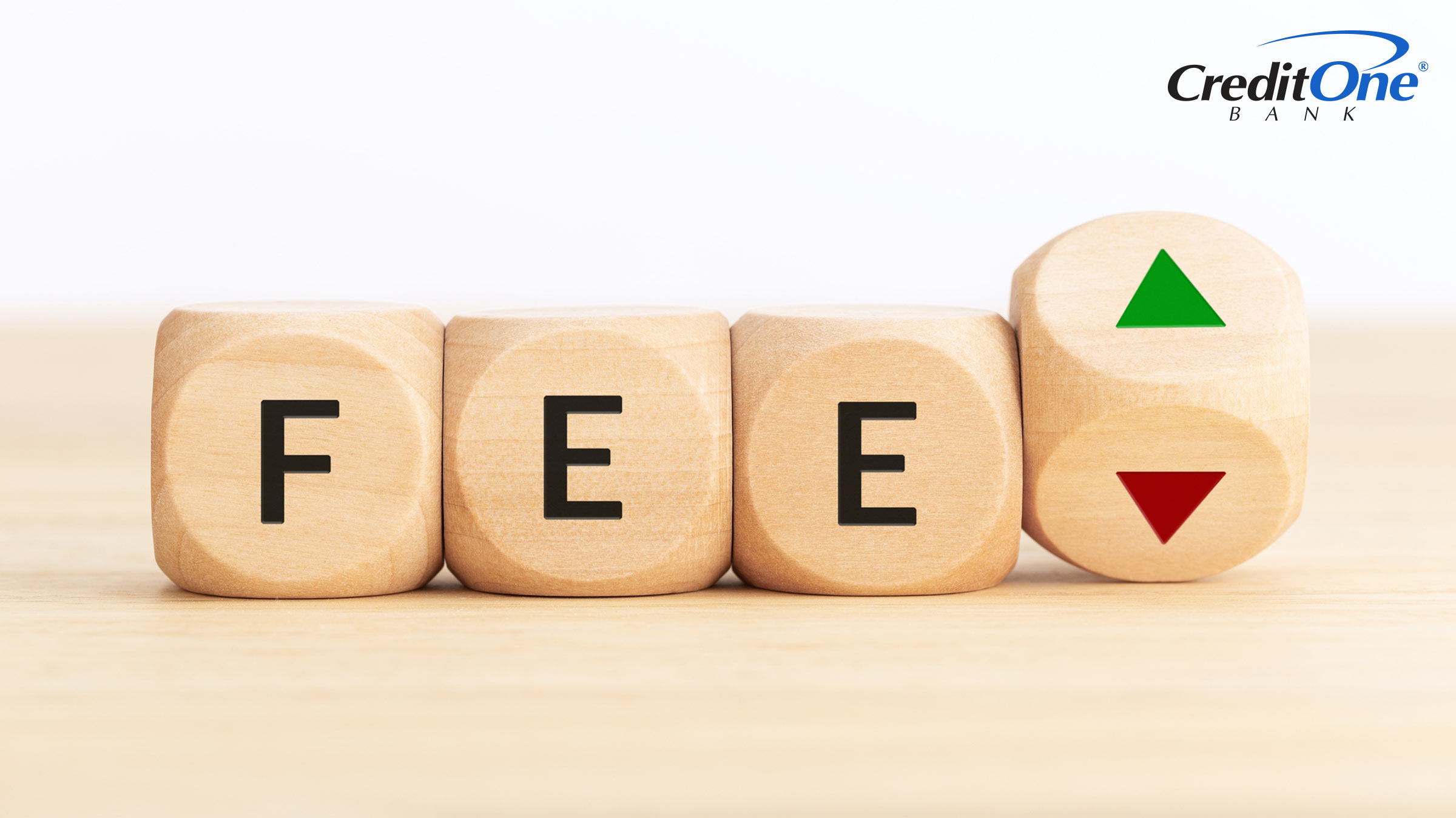 Four wooden blocks with markings on their faces are lined up in a row. The first three spell out the word “Fee,” while the last is rotating to reveal upward and downward arrows. This represents weighing the pros and cons of a credit card with an annual fee.