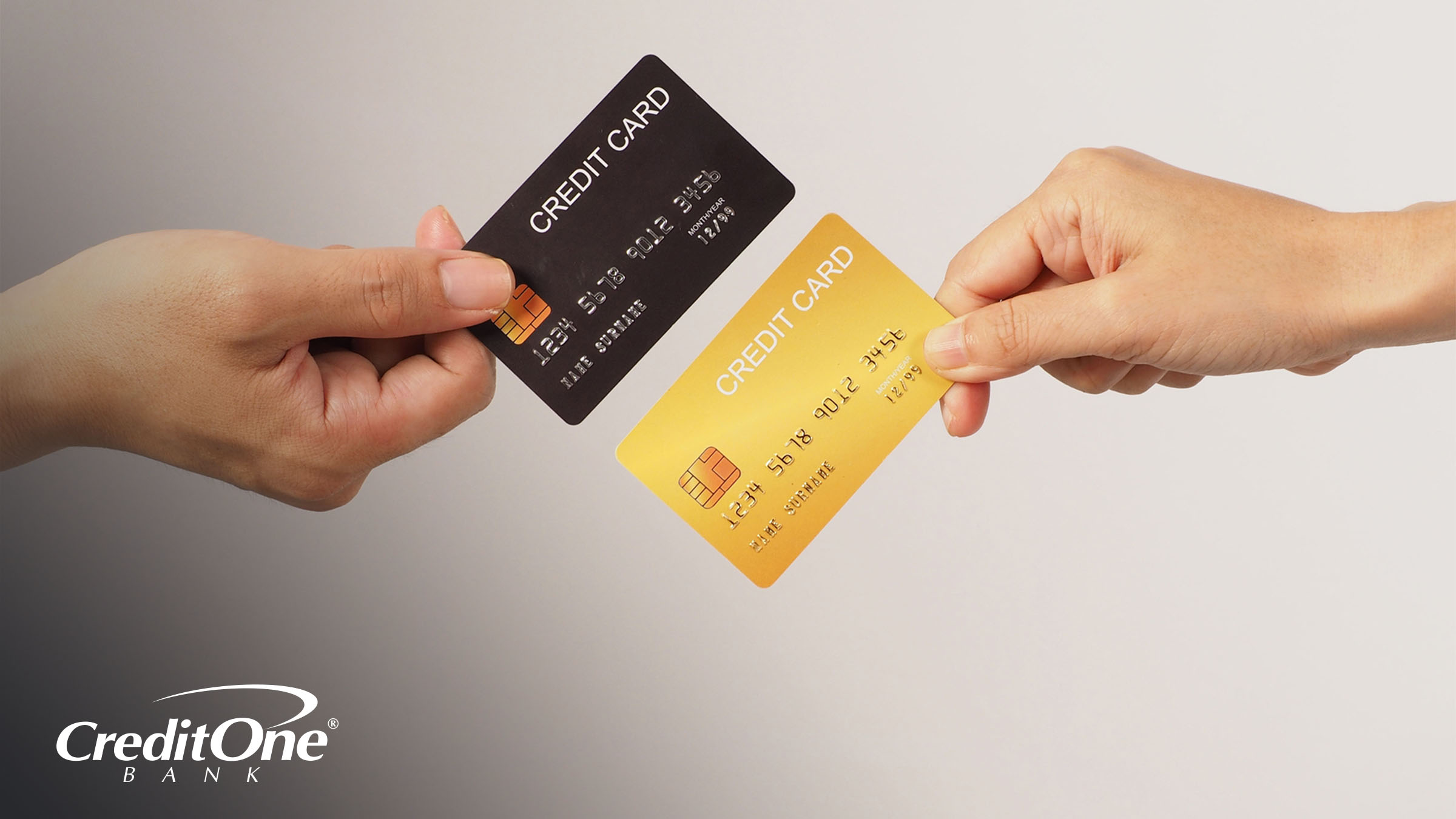 Two individuals hold different credit cards — one black, the other gold — against each other, as if comparing them. This can represent the comparison of secured and unsecured credit cards.